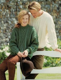 two women are sitting on a white bench and one is wearing a green cabled sweater