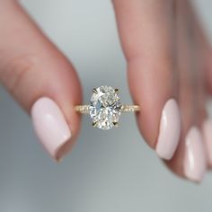 a woman's hand holding an engagement ring with a diamond on the middle finger