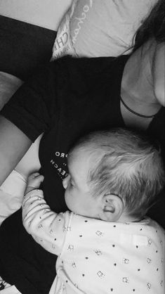 a black and white photo of a baby laying on its back next to a woman