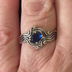 a woman's hand with a ring on it that has an oval blue stone in the middle