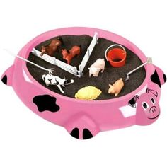 a pink and black toy tray with farm animals on it's sides, in the shape of a cow