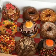 a box filled with lots of different types of donuts on top of a checkered table