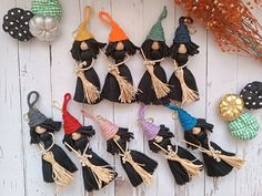 small black and white witches are hanging on the side of a wooden wall next to pumpkins