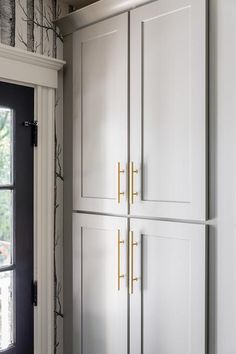 a kitchen with white cupboards and black door handles on the doors, next to a window