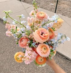 a person holding a bouquet of flowers in their hand on the side of the road