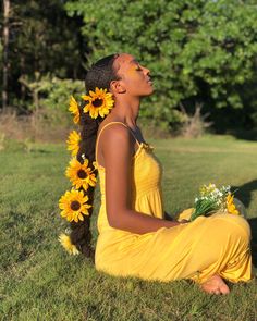 a woman sitting on the grass with sunflowers in her hair and wearing a yellow dress