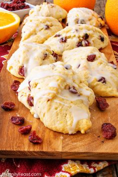 orange cranberry scones with icing on a cutting board next to sliced oranges