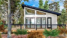 a small house in the woods with lots of trees and bushes around it, as well as a deck