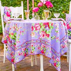 the table is covered with purple flowers and has an umbrella over it to protect it from the sun