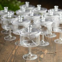 many wine glasses are lined up on a wooden table with greenery in the background