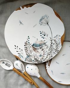 three plates and spoons are sitting next to each other on a table with dragonflies painted on them