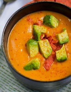 there is a bowl of soup with avocado on top