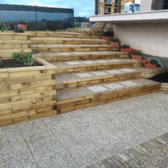 some wooden steps with plants in them on the side of a building and stairs leading up to it