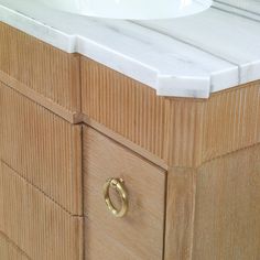 a bathroom vanity with marble top and gold handles on the cabinet door, next to a white sink