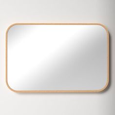 a wooden frame mirror hanging on the wall with a white wall in the back ground