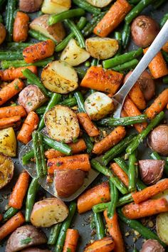 potatoes, green beans and carrots on a sheet pan with a spatula in it