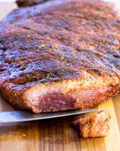 a piece of meat sitting on top of a wooden cutting board next to a knife