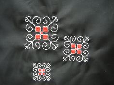 two red and white embroidered designs on a black fabric material, one with an orange square in the center