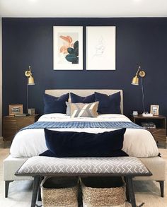 a bedroom with blue walls, white bedding and two framed pictures on the wall