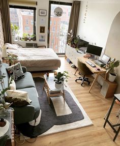 a living room filled with furniture and a large window next to a wooden floor covered in plants