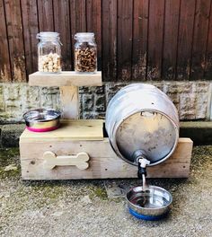 a dog food dispenser and water bowl sitting on top of a wooden crate