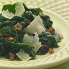 a white plate topped with greens and nuts