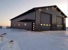 a large metal building sitting on top of a snow covered field