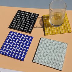 three different colored glass coasters sitting on top of a table next to a cup