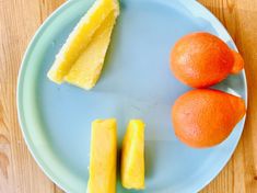 two oranges and one piece of cake are on a blue plate next to each other