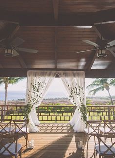 an outdoor wedding setup with white draping and floral arrangements on the back porch