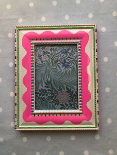 a pink and green photo frame on a polka dot tablecloth with white dots in the background