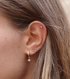 a close up of a woman's ear with two small stars attached to it