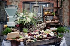 a table topped with lots of different types of cheeses and fruit on top of wooden crates