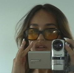 a woman with glasses holding up a camera