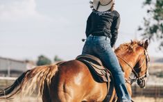 a woman riding on the back of a brown horse