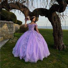 a woman in a purple dress standing under a tree