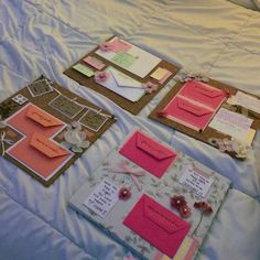 three different types of greeting cards on a bed with white sheets and pink flowers in the middle