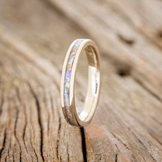 a wedding band with opalite inlays sits on a piece of wood