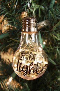 a light bulb ornament that says be the light on it hanging from a christmas tree