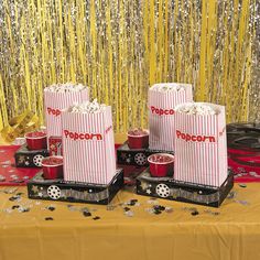 some red and white striped popcorn boxes on a table with silver confetti streamers