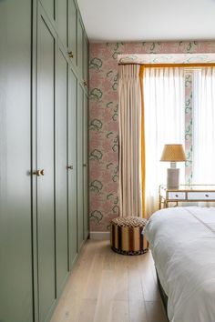 the bedroom is decorated in pastel colors and has an interesting wallpaper pattern on the walls