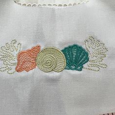 three seashells embroidered on a white shirt