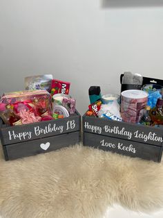 two wooden boxes filled with candy and candies on top of a fur rug next to a white wall