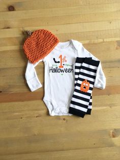 a baby's halloween outfit and leggings are laid out on a wooden floor