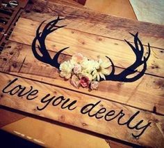 a wooden sign with flowers and antlers on it