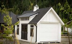 a small white shed with a black roof