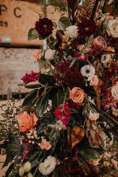 an arrangement of flowers and greenery on a table