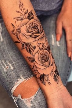 a woman's arm with roses and leaves tattooed on the side of her leg