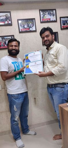 two men standing next to each other holding up a certificate