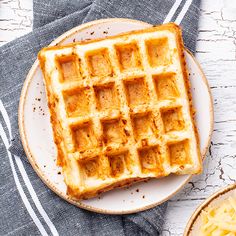 a waffle on a plate next to a bowl of macaroni and cheese